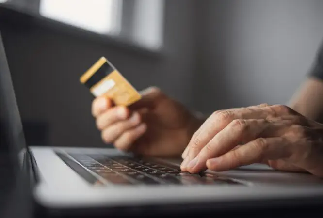 Man hand holding credit card and using laptop at home. Businessman or entrepreneur working in office. Online shopping, internet banking, store online, payment, spending money, e-commerce concept