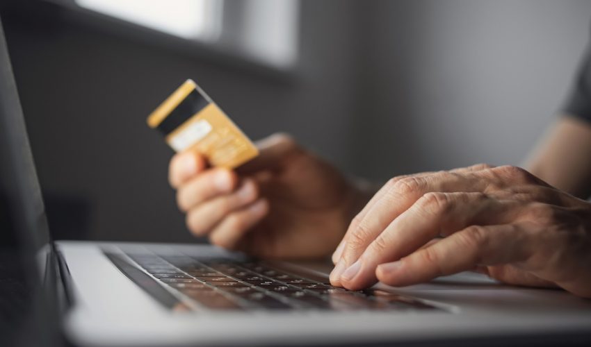 Man,Hand,Holding,Credit,Card,And,Using,Laptop,At,Home. Man hand holding credit card and using laptop at home. Businessman or entrepreneur working in office. Online shopping, internet banking, store online, payment, spending money, e-commerce concept